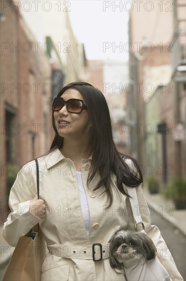 Young Asian woman with small dog in urban area