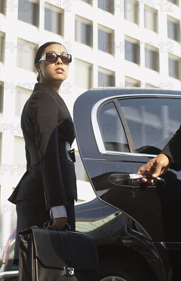 Asian businesswoman getting into town car