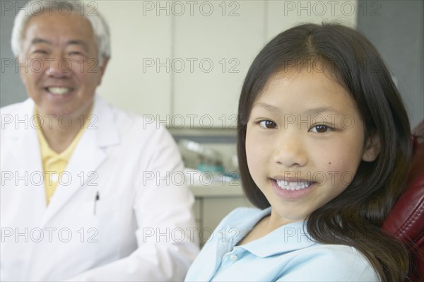 Senior Asian male dentist with young patient