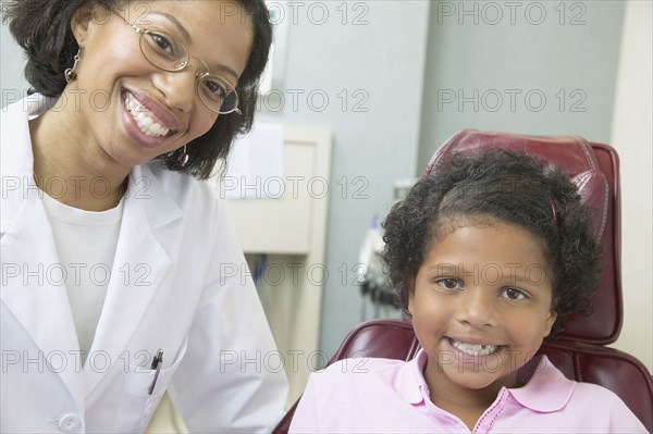 African female dentist examining young female patient
