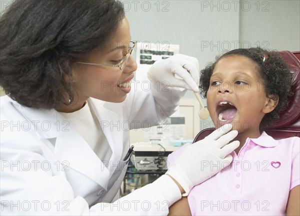 African female dentist examining young female patient