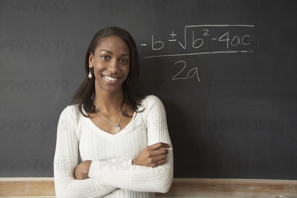 African female student next to math problem on blackboard