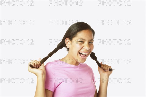 Studio shot of Hispanic girl holding her pigtails