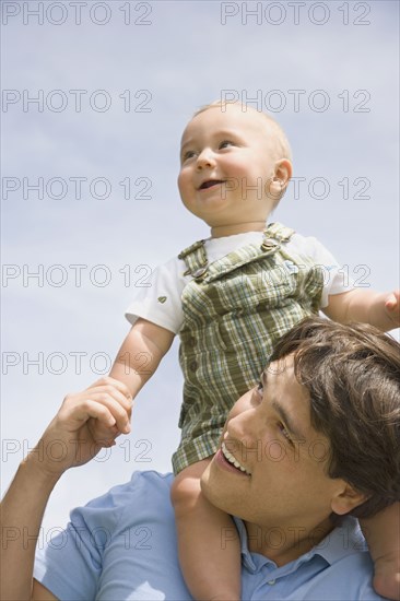 Hispanic father holding baby on shoulders