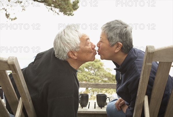 Senior Asian couple kissing outdoors