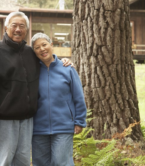 Senior Asian couple hugging and smiling outdoors