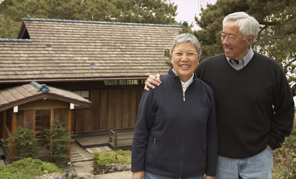 Senior Asian couple smiling and hugging outdoors