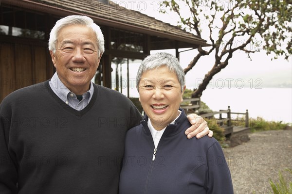 Senior Asian couple smiling and hugging outdoors