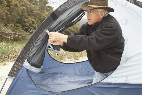 Senior Asian man opening tent