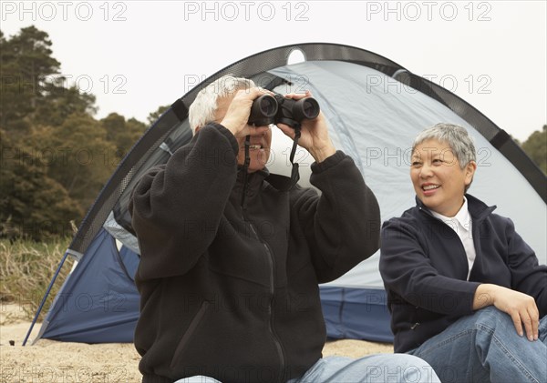 Senior Asian couple camping with binoculars