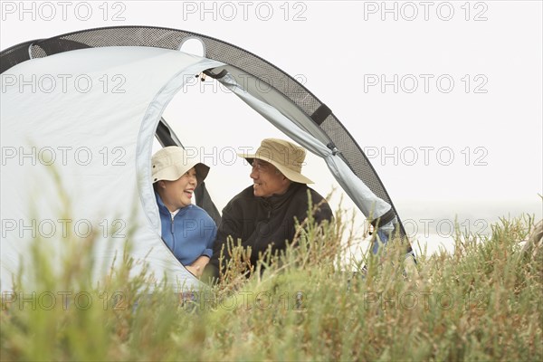 Senior Asian couple sitting in tent smiling