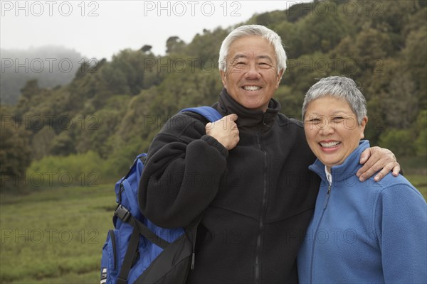 Senior Asian couple with backpack outdoors