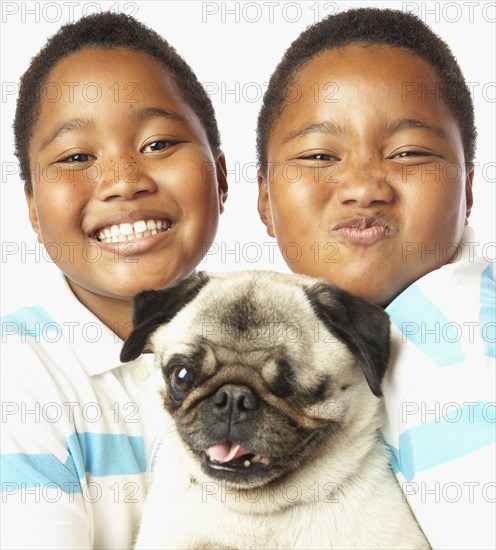 Young African twin brothers holding small dog