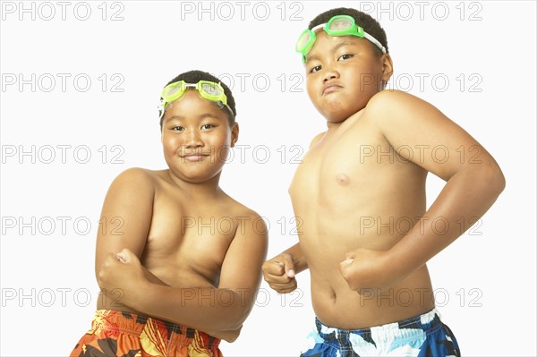 Young African twin brothers in bathing suits flexing