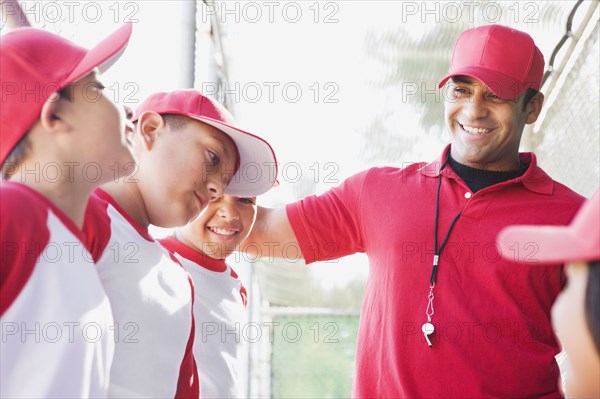 Multi-ethnic boys in baseball uniforms with coach