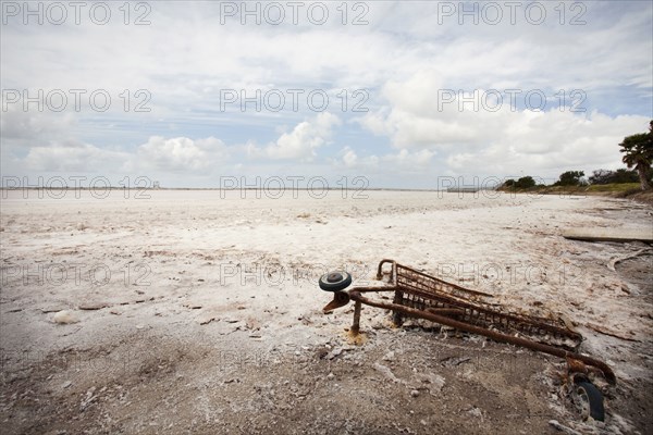 Rusted shopping cart buried in sand