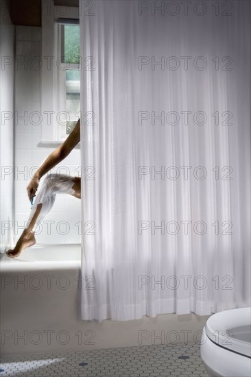 Korean woman shaving her legs in shower
