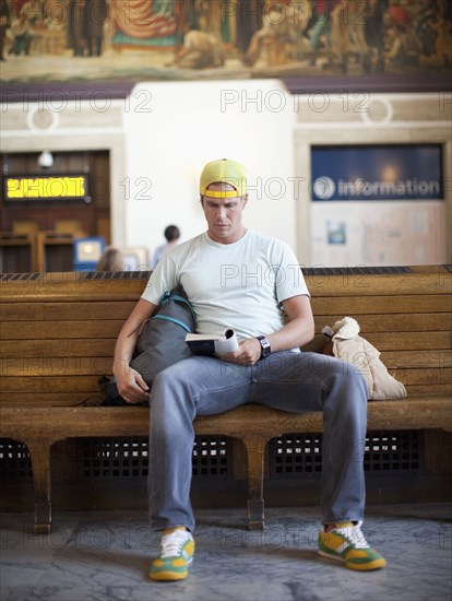 Caucasian man reading book in train station