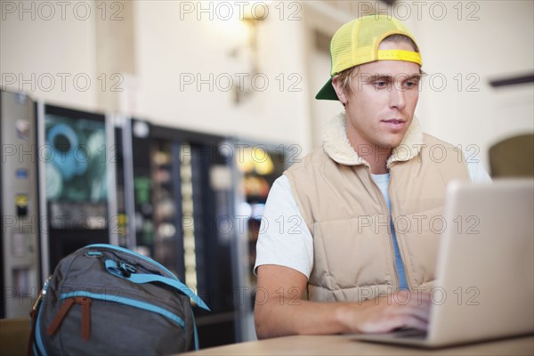 Caucasian man using laptop in cafeteria