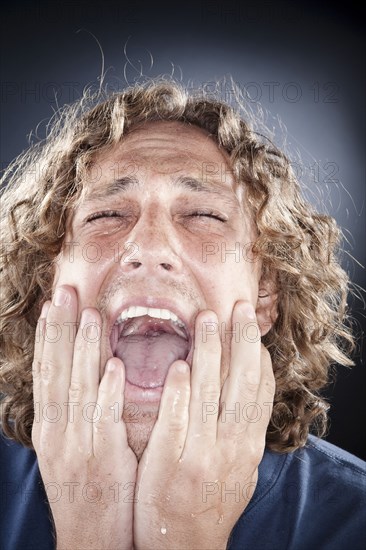 Caucasian man shouting with head in hands