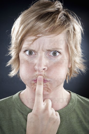 Caucasian woman holding finger over her mouth