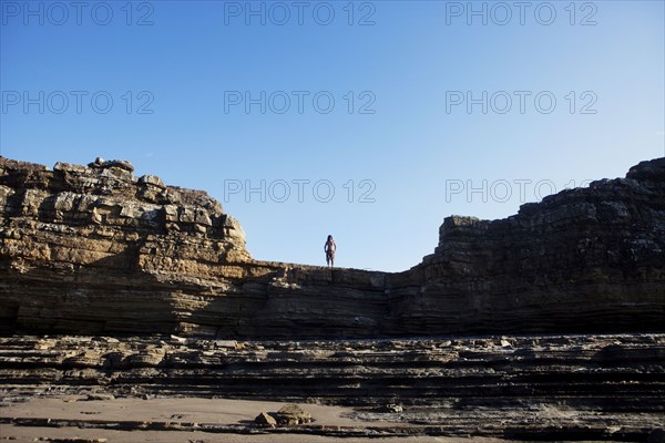 Asian man standing on cliff's edge