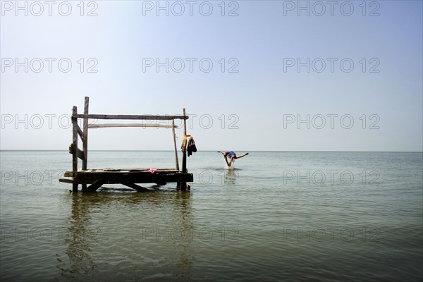 Person jumping from pier into ocean