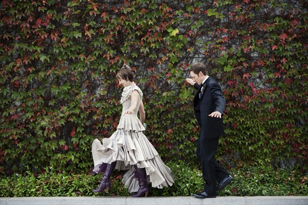 Bride and broom walking on ledge