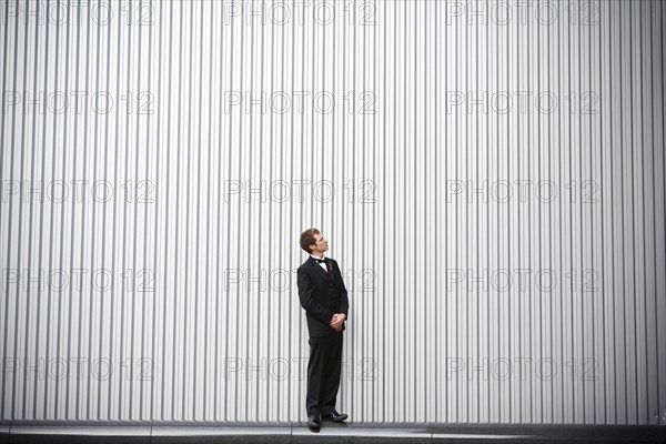 Uncertain groom standing near wall