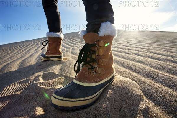 Person wearing boots standing in sand