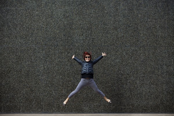 Korean woman jumping on city sidewalk