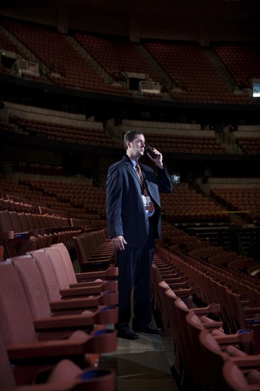 Businessman using walkie-talkie in empty auditorium