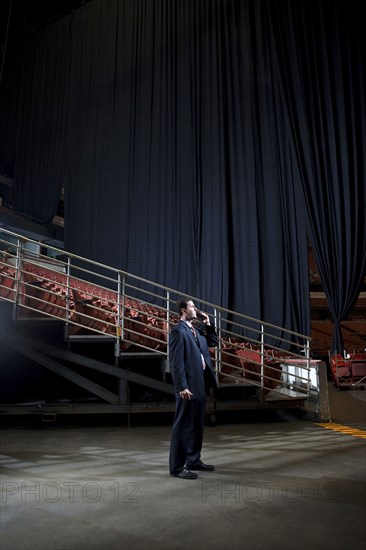 Businessman using walkie-talkie in empty auditorium