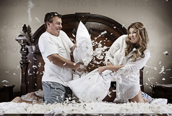 Caucasian couple having pillow fight