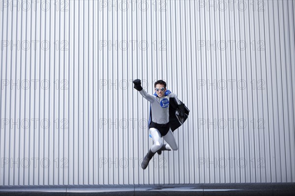 Caucasian man jumping in superhero costume