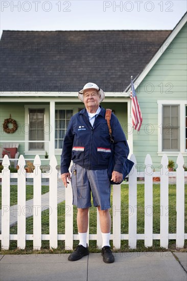 Caucasian mailman standing on sidewalk