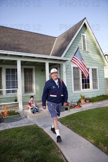 Caucasian mailman walking in front yard