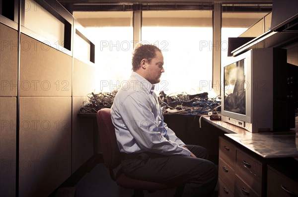 Caucasian businessman watching television at desk