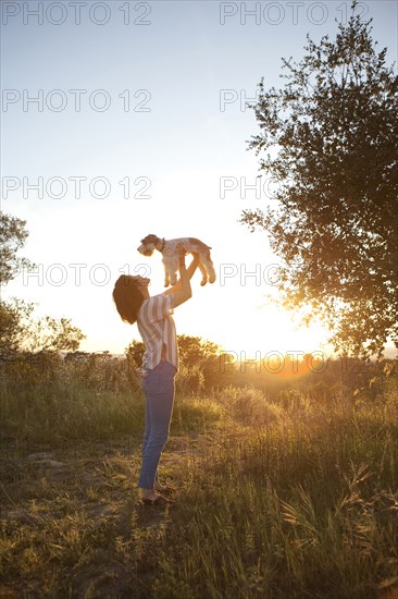 Korean woman playing with dog in meadow