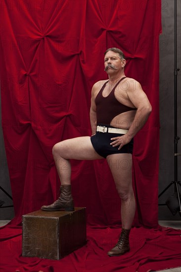 Caucasian weight lifter posing by curtain