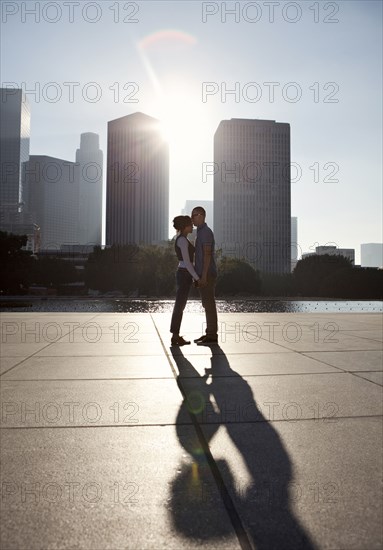 Couple casting shadows on urban waterfront