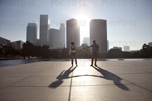 Couple casting shadows on urban waterfront