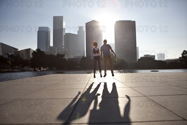 Couple casting shadows on urban waterfront