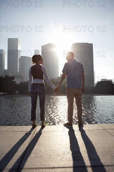 Couple casting shadows on urban waterfront