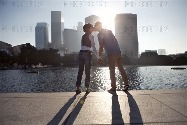 Couple casting shadows on urban waterfront