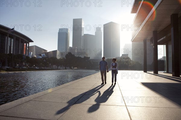 Couple casting shadows on urban waterfront