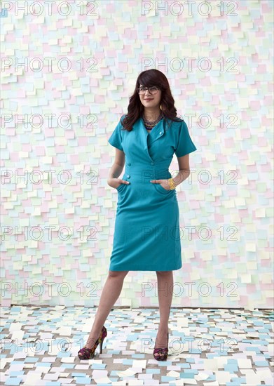 Mixed race businesswoman by wall of sticky notes