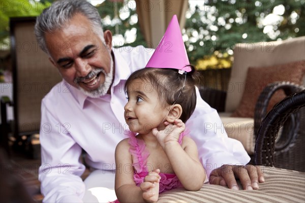 Grandfather sitting with granddaughter at birthday party