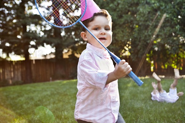 Caucasian children playing badminton in backyard