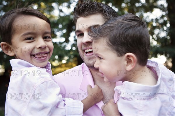 Caucasian father holding sons outdoors